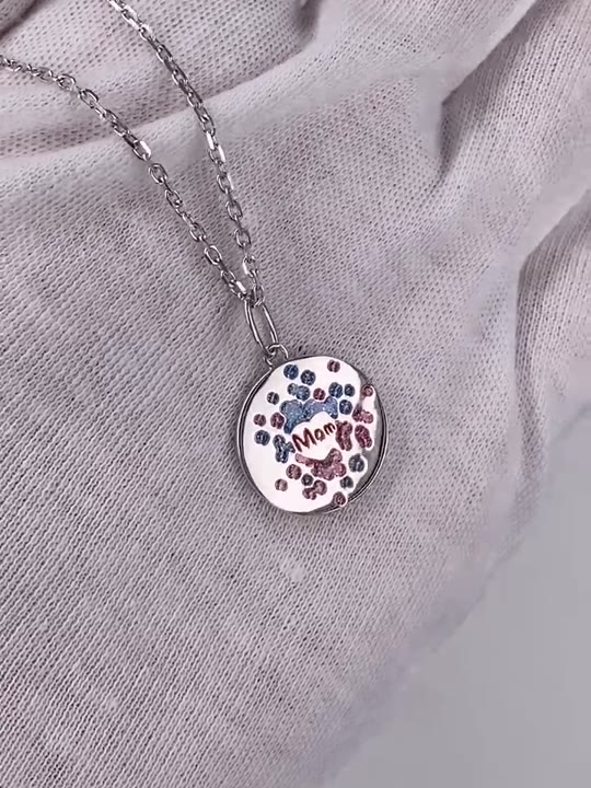 A round silver pendant with pink and blue enamel dots